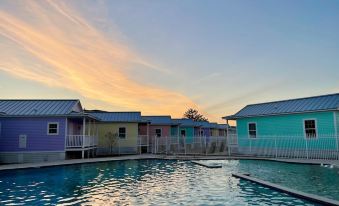 a row of colorful houses with a swimming pool in the foreground , surrounded by a fence at Key West Cottages