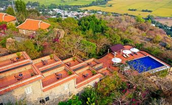 aerial view of a small village surrounded by trees and hills , with a house surrounded by trees at Victoria Nui Sam Lodge