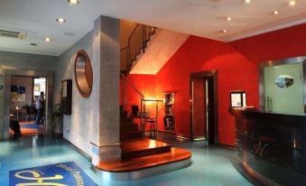 a hotel lobby with a red wall , a blue reception desk , and a staircase leading to the second floor at Panorama Hotel