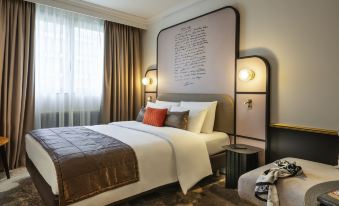 a large bed with a white comforter and pillows is in the middle of a room at Mercure Versailles Paris Ouest