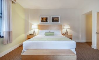a large bed with white linens and a wooden headboard is situated between two nightstands , flanked by lamps at Rhythm