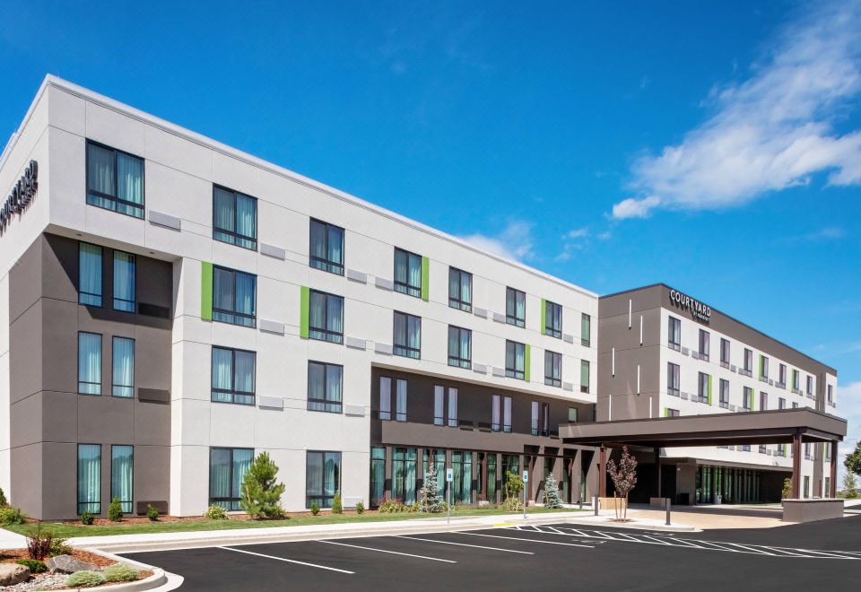 a modern , white building with green and gray accents , surrounded by a parking lot and clear blue sky at Courtyard Pasco Tri-Cities Airport