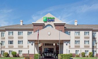 a holiday inn express hotel with a red brick building , green lawn , and american flag at Home2 Suites by Hilton Ogden
