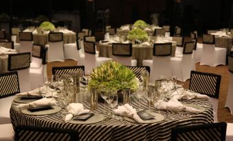 a well - decorated banquet hall with tables covered in black and white striped tablecloths , glasses , and flowers at Heritance Kandalama