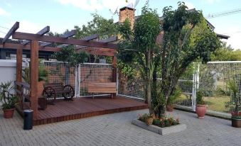 a large tree in a courtyard , surrounded by a wooden deck and brick wall , with a bench and a bench in the background at North Hotel - Aeroporto