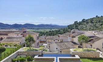 a beautiful villa with a swimming pool , surrounded by lush green gardens and mountains in the background at Cap Vermell Grand Hotel