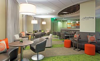 a modern hotel lobby with various seating options , including couches , chairs , and a dining table at Even Hotel Rockville - Washington, DC Area, an IHG Hotel