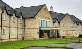 a large , modern building with a stone facade and a clock tower on the first floor at Best Western Plus Pastures Hotel