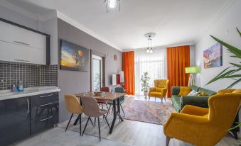 a modern living room and dining area with a gray wall , orange curtains , and yellow chairs at Prime Inn