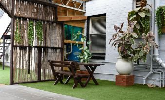 a wooden bench and table are placed on a grassy area next to a glass wall at Hobart Tower Motel