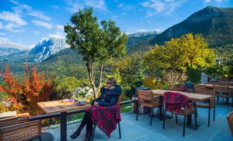 a man is sitting at a dining table , enjoying a cup of coffee on a sunny day in front of a mountain view at Aristi Mountain Resort