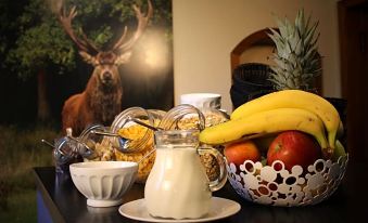 a dining table with a variety of food items , including bowls of cereal , bananas , and apples at Hotel am Kurpark