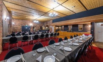 a large dining room with multiple tables and chairs , all set for a formal event at Golden Age Motor Inn