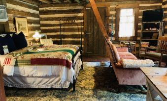 a cozy bedroom with wooden walls , a bed covered in a quilt , and a couch situated in the corner at Coulter Farmstead