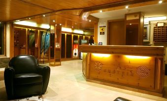 a modern hotel lobby with wooden ceiling , white marble floors , and a black leather chair at Hotel Austria