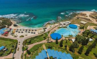 a bird 's eye view of a resort with a pool and beach area , surrounded by lush greenery at Resort Hadera by Jacob Hotels