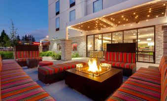 an outdoor seating area at a hotel , with several couches and chairs arranged around a fire pit at Home2 Suites by Hilton Marysville