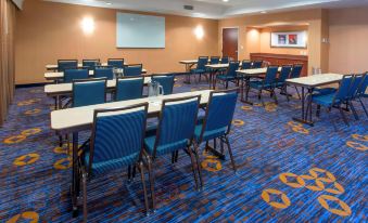 a conference room with rows of blue chairs and tables , a projector screen , and a bar at Courtyard by Marriott Montgomery Prattville