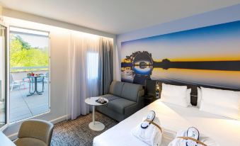 a hotel room with a large bed , couch , and table , along with a painting on the wall at Novotel Toulouse Centre Compans Caffarelli