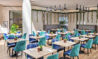 a large dining area with multiple tables and chairs , some of which are blue in color at Sofitel London Gatwick