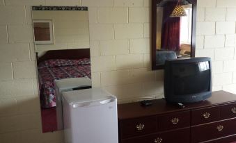 a small kitchen area with a refrigerator , microwave , and microwave on a dresser next to a bed at H&K Motel