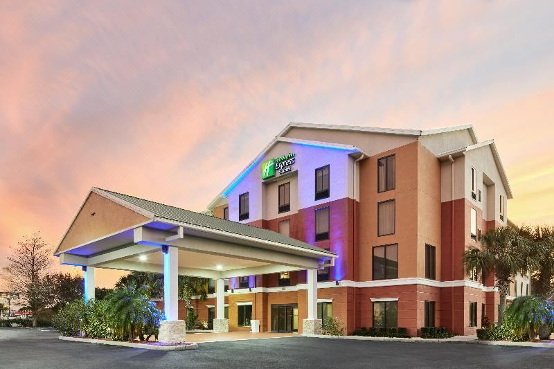 a large , modern hotel with a blue sign and red brick exterior , surrounded by palm trees and other greenery at Homewood Suites by Hilton Tampa-Port Richey