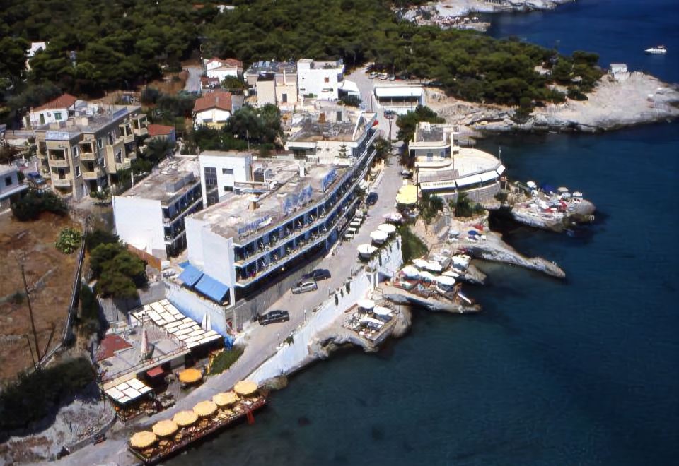 an aerial view of a coastal town with boats docked at a marina , surrounded by buildings and trees at Argo Spa Hotel