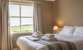 a neatly made bed with white sheets and towels is situated next to a window in a room at Purdy Lodge