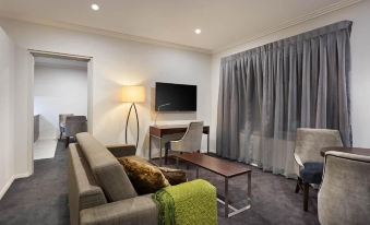 a modern living room with a couch , a chair , and a tv . also a dining table in the room at Attika Hotel