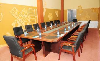 a long wooden conference table with multiple chairs arranged in a row , along with water bottles on the table at Silver Springs Hotel Uganda