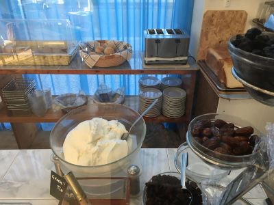 a dining table with various food items , including cakes , bread , and other pastries , as well as a cup of coffee at Hotel Summery