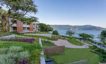 a large house with a garden and a lake in the background , surrounded by grass and trees at Wyndham Ilhabela Casa di Sirena
