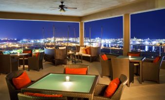 a rooftop patio with a pool table , chairs , and couches , overlooking the city at night at Sheraton Puerto Rico Resort & Casino