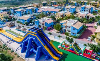a colorful amusement park with a slide and water slide in front of blue houses at Kunuku Resort All Inclusive Curacao, Trademark by Wyndham