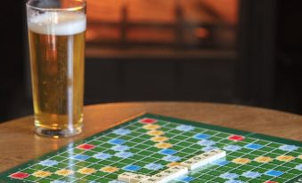 a glass of beer and a game board are sitting on a table in front of a fireplace at The Ferry Boat Inn