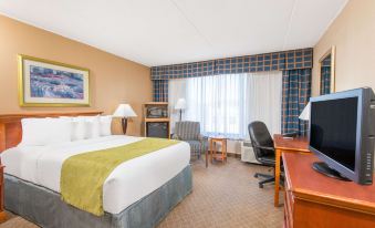 a hotel room with a king - sized bed , a desk , and a flat - screen tv . also a chair in the room at Ramada by Wyndham Cumberland Downtown