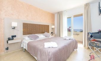 a bedroom with a large bed , white sheets , and a view of the ocean through the window at Hotel Sa Barrera - Adults Only