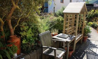 a small wooden house surrounded by a garden , with a table and chairs set up for outdoor dining at Acorns Guest House