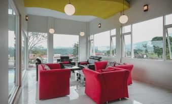 a modern living room with red chairs and a large window overlooking the outdoors , creating a relaxing atmosphere at RedDoorz Syariah @ Jalan Dieng