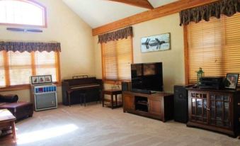 a spacious living room with hardwood floors , a large flat - screen tv mounted on the wall , and a piano in the corner at Oak Creek Lodge