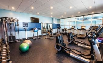 a well - equipped gym with various exercise equipment , including treadmills and weightlifting machines , under bright lights at Four Points by Sheraton Allentown Lehigh Valley
