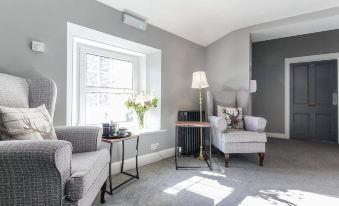 a cozy living room with grey walls , white furniture , and a window overlooking the outdoors at The Greenhead Hotel