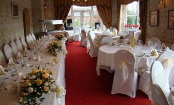 a beautifully decorated banquet hall with tables covered in white tablecloths and chairs arranged for a formal event at Woodlands Hotel
