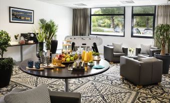 a dining area with a round table , several chairs , and a variety of food and drinks on the table at Best Western Plus Hotel les Rives du Ter