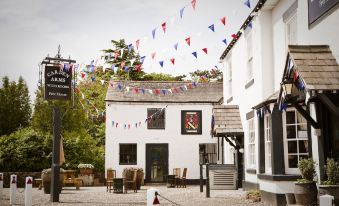 a white building with a sign on the side , surrounded by flags and other decorations at The Carden Arms