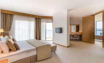 a modern hotel room with a large bed , a television , and a balcony overlooking the ocean at Grand Hotel Ontur Cesme