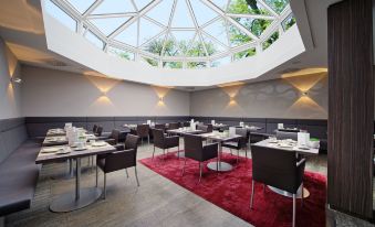 a modern dining room with a round glass ceiling , allowing natural light to fill the space at Hotel HerzogsPark