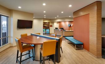 a modern hotel lobby with a round table , chairs , and a blue bench , as well as a desk and chairs in the background at TownePlace Suites Clovis