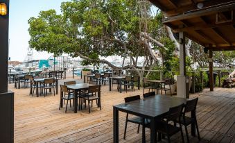 an outdoor dining area with wooden tables and chairs , surrounded by a beautiful view of the ocean at Marina de Salinas