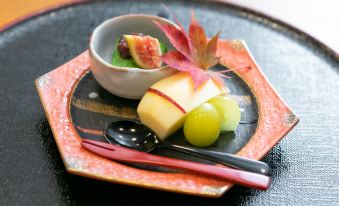 a plate with a bowl of fruit and a cup of soup on a dining table at Okushiga Kogen Hotel